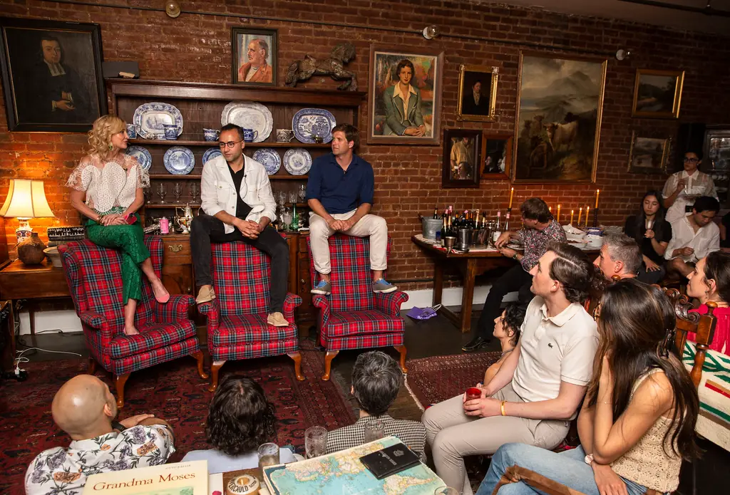 A panel discussion in a candlelit room, three speakers seated in front of a close audience
