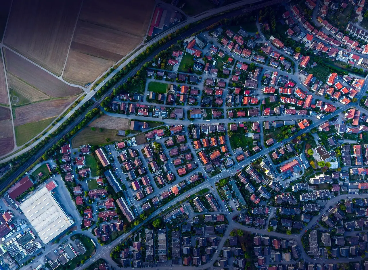 High-resolution aerial imagery of a Lusaka neighbourhood, individual roofs and the roads between them legible from the air