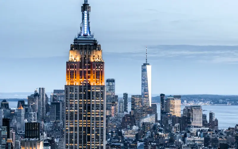 The Manhattan skyline at dusk, the Empire State Building lit in the foreground and Lower Manhattan behind it