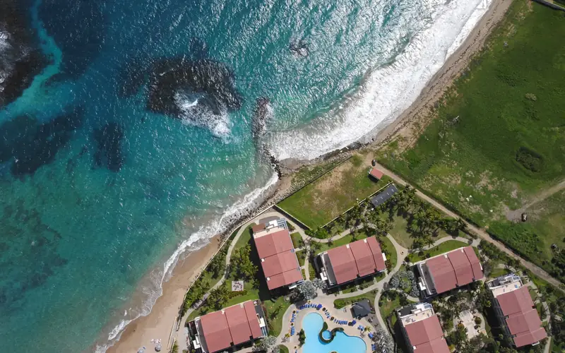 Aerial photography of the St. Kitts coastline, individual buildings and property boundaries legible against the shore